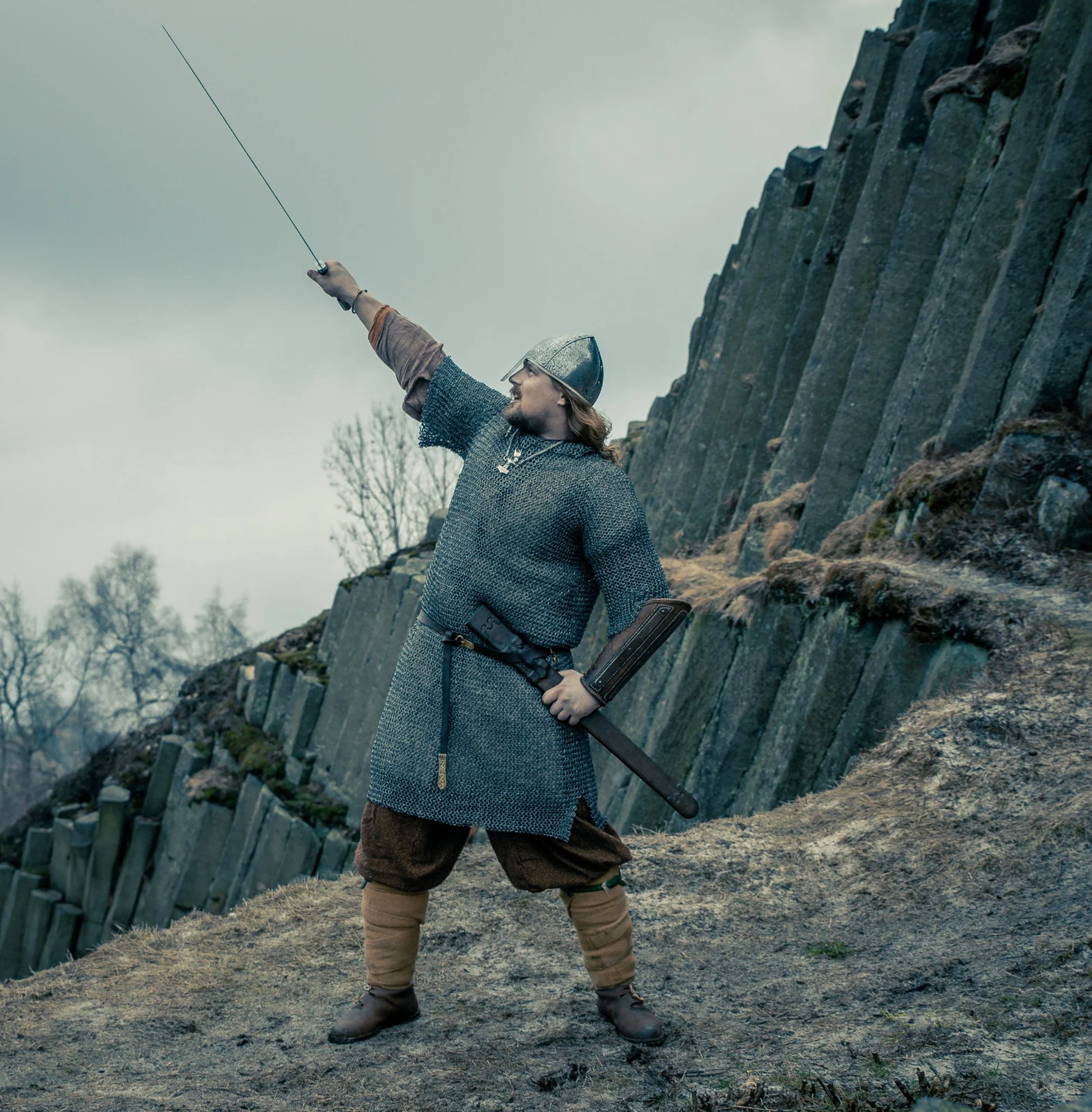Swordsman in chain mail and a helmet holding a raised sword