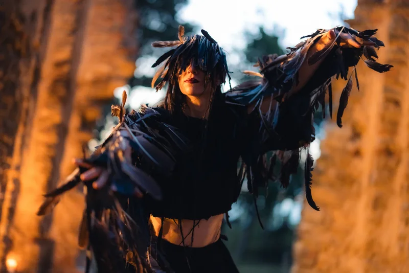 Danzatrice in costume nero con maniche di piume